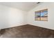 Clean, empty bedroom featuring neutral walls, carpeted floors, and a view to the outside at 14994 W Charter Oak Rd, Surprise, AZ 85379