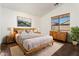 Comfortable main bedroom with natural wood furniture, neutral colored walls, and a bright window at 14994 W Charter Oak Rd, Surprise, AZ 85379