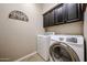 Laundry room with a side-by-side washer and dryer and dark cabinets above for extra storage at 17083 S 182Nd Ave, Goodyear, AZ 85338