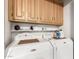 Laundry room with a side-by-side washer and dryer and wooden cabinets above at 17200 W Bell Rd # 1628, Surprise, AZ 85374
