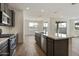 A modern kitchen with gray cabinets, stainless steel appliances, and a large island with seating, flowing into a dining area at 17300 W Dahlia Dr, Surprise, AZ 85388