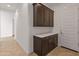 Hallway with dark cabinets, white walls, tan tile and white door at 17347 W Chama Dr, Surprise, AZ 85387