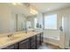 Bright bathroom featuring double sinks, vanity mirror, tub, and enclosed shower space for added convenience at 25742 N 103Rd Dr, Peoria, AZ 85383