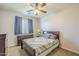 Cozy bedroom with a ceiling fan, dresser, and a comfortable bed with patterned quilt at 25742 N 103Rd Dr, Peoria, AZ 85383