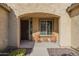 Inviting front porch with seating, decorative plants, and an arched entryway at 25742 N 103Rd Dr, Peoria, AZ 85383