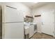 Functional laundry room equipped with washer, dryer, storage shelves, and a door, optimizing household tasks at 25742 N 103Rd Dr, Peoria, AZ 85383