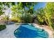 Lush backyard oasis with a sparkling pool, stone waterfall feature, and mature landscaping for privacy at 2744 E Donato Dr, Gilbert, AZ 85298