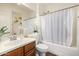 Bathroom with wood vanity, large mirror, tub with shower and shower curtain at 2744 E Donato Dr, Gilbert, AZ 85298