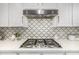 Close up shot of the gas cooktop with stainless steel vent hood and decorative tile backsplash at 2744 E Donato Dr, Gilbert, AZ 85298