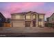 Two-story home featuring a driveway, a two-car garage, and solar panels on the roof at sunset at 3124 W Redbird Rd, Phoenix, AZ 85083