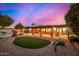 Expansive backyard featuring a pool, covered patio, and lush landscaping at dusk at 3226 E Lazy Ln, Phoenix, AZ 85028