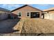 Back exterior view of home, showing a covered patio, a large empty yard, and desert landscaping at 40995 W Portis Dr, Maricopa, AZ 85138