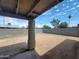 View of the large dirt backyard from a covered patio with block wall and palm trees at 4124 E Apollo Rd, Phoenix, AZ 85042