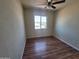 Bedroom featuring wood-look floors, ceiling fan and view of the neighborhood through the window at 4124 E Apollo Rd, Phoenix, AZ 85042
