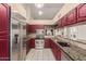 Modern kitchen with stainless steel appliances, granite countertops, and sleek red cabinetry at 607 W Palo Verde St, Gilbert, AZ 85233