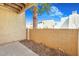 Enclosed patio featuring a tan block wall and a mature palm tree against a sunny sky at 8055 E Thomas Rd # A102, Scottsdale, AZ 85251