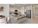 Bright kitchen features white cabinets, stainless steel appliances, a granite island, and seating for four at 9832 W Agora Ln, Tolleson, AZ 85353