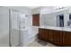 Bathroom featuring double sinks, wood cabinets, a tub, and a glass-enclosed shower at 10721 W Jefferson St, Avondale, AZ 85323