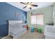 A bedroom features a ceiling fan, a crib, a changing table, carpet flooring, and colorful walls at 10721 W Jefferson St, Avondale, AZ 85323