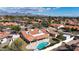 Aerial view of a home with a red tile roof, pool, lush landscaping, and mountain views in the distance at 12448 N 76Th St, Scottsdale, AZ 85260