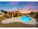 Relaxing backyard oasis with pool, covered patio, and desert landscaping under a colorful dusk sky at 12448 N 76Th St, Scottsdale, AZ 85260