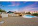 Backyard showcasing private pool, covered patio, and low maintenance landscaping against a dusk sky at 12448 N 76Th St, Scottsdale, AZ 85260
