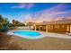 Lush backyard with sparkling pool, covered patio, and serene landscaping at sunset at 12448 N 76Th St, Scottsdale, AZ 85260