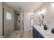 Modern bathroom features a glass-enclosed shower, dual sink vanity with navy cabinets, and neutral toned stone flooring at 12448 N 76Th St, Scottsdale, AZ 85260