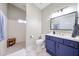 Bathroom featuring blue vanity, white countertops, and a walk-in shower with a wood bench at 12448 N 76Th St, Scottsdale, AZ 85260