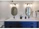 Bathroom with double sinks, navy blue cabinets, matte black hardware, and decorative oval mirrors at 12448 N 76Th St, Scottsdale, AZ 85260