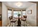 Bright breakfast nook features seating for two, a round wooden table, and natural light from the bay windows overlooking the pool at 12448 N 76Th St, Scottsdale, AZ 85260