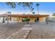The backyard has a covered patio, rock landscaping, a small palm tree and mature landscaping in background at 14013 N 57Th Pl, Scottsdale, AZ 85254