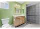 Green-walled bathroom featuring a wooden vanity, modern fixtures, and an accessible tiled shower at 14013 N 57Th Pl, Scottsdale, AZ 85254