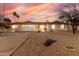 Charming ranch-style home featuring a two-car garage and desert landscaping, set against a vibrant sunset sky at 14013 N 57Th Pl, Scottsdale, AZ 85254