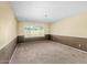 Neutral room with two-tone paint, carpeted floors, and a large window offering plenty of natural light at 14013 N 57Th Pl, Scottsdale, AZ 85254