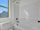 Bright bathroom features a shower-tub combination with white tile and a window letting in natural light at 14247 W Bronco Trl, Surprise, AZ 85387