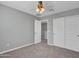 Neutral bedroom with carpet, a ceiling fan, white closet doors and an open door to a hallway at 14247 W Bronco Trl, Surprise, AZ 85387