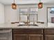 Granite countertop island and stainless steel sink fixture with modern lighting at 14247 W Bronco Trl, Surprise, AZ 85387
