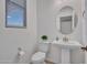 Cozy powder room with a pedestal sink, oval mirror, and ample natural light at 14247 W Bronco Trl, Surprise, AZ 85387