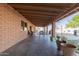 Large covered patio with a brick wall, exposed beam ceiling, and an outdoor dining area at 14251 N 182Nd Ave, Surprise, AZ 85388
