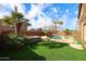 Expansive backyard featuring a pool, spa, artificial grass, and lush landscaping at 17641 W Corrine Dr, Surprise, AZ 85388
