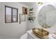 Stylish powder room with a unique gold sink, modern art, and decorative shelving for a charming, contemporary feel at 17641 W Corrine Dr, Surprise, AZ 85388