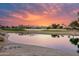 Tranquil pond reflecting a brilliant sunset sky, complemented by lush green landscaping at 17859 N Peppermill Ln, Surprise, AZ 85374