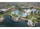 Stunning aerial perspective of a community with pools, a lake, palm trees, and lush landscaping under a partly cloudy sky at 19973 N Monte Ln, Maricopa, AZ 85138