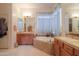 Bright bathroom featuring dual sinks, soaking tub, and tiled accents at 19973 N Monte Ln, Maricopa, AZ 85138