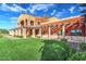 Well-maintained building exterior with a green lawn, terra cotta walls, arched walkway, and covered porch at 19973 N Monte Ln, Maricopa, AZ 85138