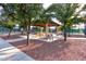 Serene park setting featuring picnic tables under a pergola surrounded by lush trees and winding sidewalks at 19973 N Monte Ln, Maricopa, AZ 85138