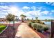 Inviting walkway surrounded by lush greenery leading to a sparkling pool with lounge chairs under a partly cloudy sky at 19973 N Monte Ln, Maricopa, AZ 85138