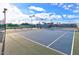 Well-maintained outdoor tennis court featuring vibrant blue playing surface, net, and outdoor lighting under a sunny sky at 19973 N Monte Ln, Maricopa, AZ 85138