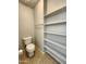 Bathroom with tile flooring has a toilet, towel rack, and shelving unit at 2009 E Lindrick Dr, Gilbert, AZ 85298